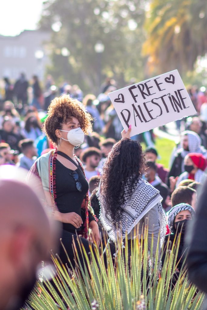 UK Acts to Combat Settler Violence in the West Bank woman in black and white long sleeve shirt holding white and blue signage